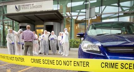 Forensic science students in overalls stood behind yellow crime scene tape