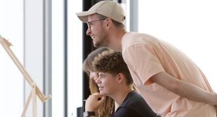 A tutor looking at a canvas and smiling