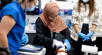 Dental student doing practical work on a phantom head with the help of a tutor