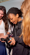 A student fashion designer looking down at their camera